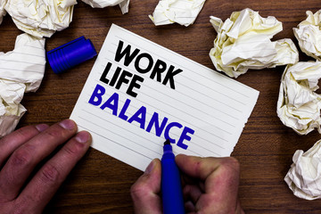 Writing note showing Work Life Balance. Business photo showcasing Division of time between working or family and leisure Hand holding marker write words paper lob scatter around woody desk