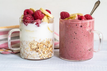 Banana, raspberry, oatmeal and yogurt smoothies and ingredients in two glass cups