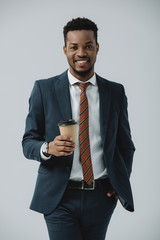 cheerful african american businessman holding paper cup isolated on grey