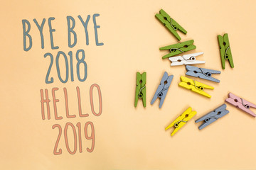 Text sign showing Bye Bye 2018 Hello 2019. Conceptual photo Starting new year Motivational message 2018 is over Yellow base with painted texts colorful paper clips laid randomly on ground © Zofia
