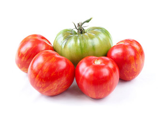 Large green and a few ripe red tomatoes on a white background