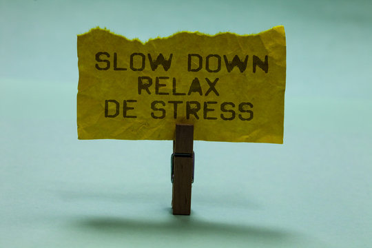 Text sign showing Slow Down Relax De Stress. Conceptual photo Have a break reduce stress levels rest calm Paperclip hold torn yellow page written brown words sky blue background