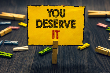 Word writing text You Deserve It. Business concept for Reward for something well done Deserve Recognition award Blacky wooden desk laid paper clip randomly one hold yellow board with text