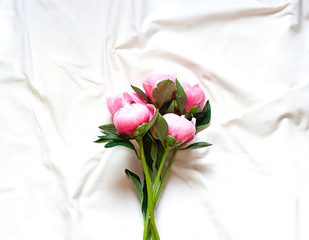 Peony flowers on the white cotton blanket. Concept floral top view,