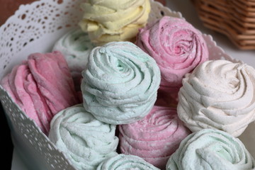 Marshmallows of different colors and shapes. Some in the shape of a flower. Stacked in gift boxes. View from above.