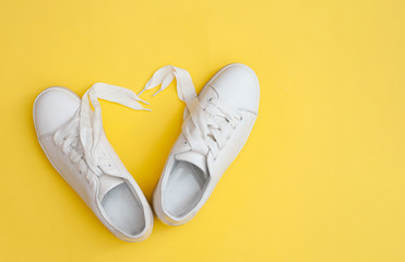 Pair of white sneakers on color background, top view