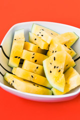 cut off triangular slices of ripe yellow watermelon in white plate