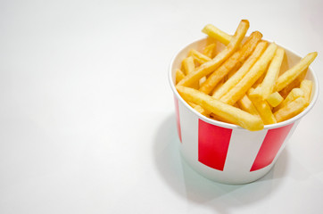 French fries potatoes in the big red-white bucket. Fast food dish on the white background. Junk food theme.