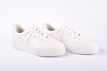 A pair of white sneakers on the white background