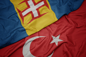 waving colorful flag of turkey and national flag of madeira.