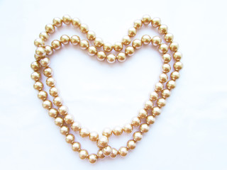 Beautiful mother-of-pearl light beads on a thread in the form of a big heart isolated object on a white background.