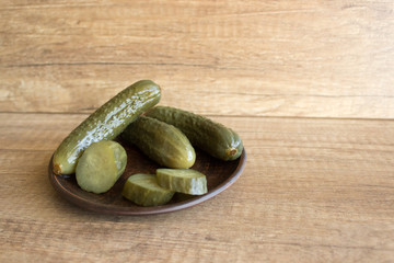 Pickled cucumbers on a clay plate. Pickles on a wooden table. Rustic style