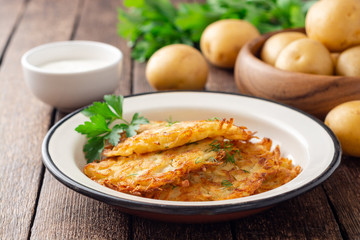 Potato pancakes or latkes or draniki in plate on dark wooden table. Selective focus.