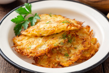 Potato pancakes or latkes or draniki in plate on dark wooden table. Selective focus.