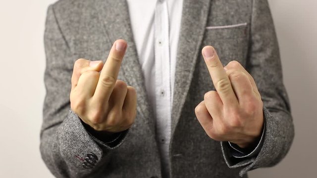 Solid caucasian man in gray jacket and speckled shirt on white background showing his middle fingers on both hands and shake it. disrespectful flip off finger sign, gesture to ill-wishers and envious