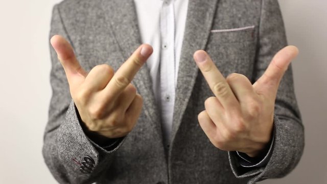 Solid caucasian man in gray jacket and speckled shirt on white background showing his middle fingers on both hands and shake it. disrespectful flip off finger sign, gesture to ill-wishers and envious