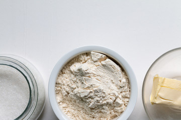 White rye organic flour, sugar and butter in a white bowl isolated, top view with space for text