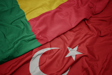 waving colorful flag of turkey and national flag of benin.