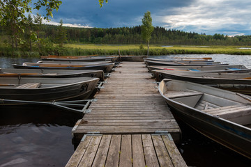 Obraz premium Beautiful view in the evening at the blue hour of row boats at the landing stage at lake Safssjon region Dalarna in Sweden