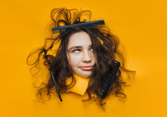 A funny teenage girl with problematic curly hair expresses displeasure on her face. Three combs...