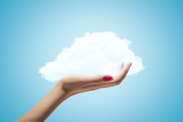 Female hand holding white cloud on blue background