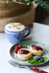 Cheesecakes with raspberry jam, berries and mint leaves served with a cup of latte