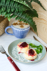 Cheesecakes with raspberry jam and mint leaves served with a cup of latte