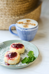 Cheesecakes with raspberry jam and mint leaves served with a cup of latte