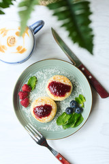Cheesecakes with raspberry jam, berries and mint leaves served with a cup of latte