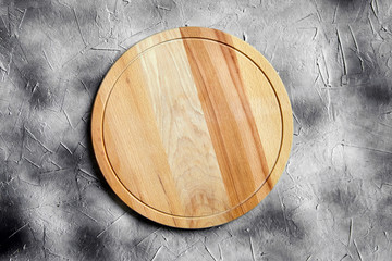 Empty round cutting board from beech wood on stone table, grey background, top view