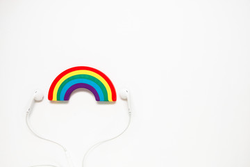 white headphones and rainbow on white background with copy space