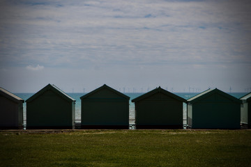Fototapeta na wymiar seascape of beach huts with wind turbines on the horizon