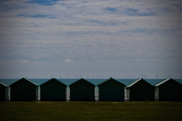 Obraz premium seascape of beach huts with wind turbines on the horizon