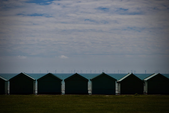 seascape of beach huts with wind turbines on the horizon