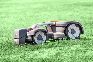 Robot automatic lawn mower working on a grass. New technologies concept © EdNurg