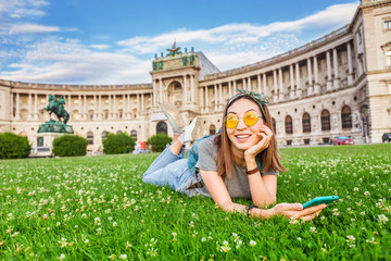 Young asian woman using her smartphone for internet surfing lying on a green grass in Vienna