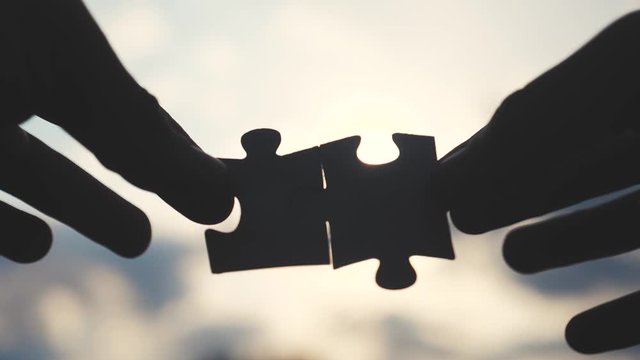 teamwork business finance concept. male hands connect two puzzles silhouette against the sunset lifestyle. symbol teamwork of association and connection. strategy business