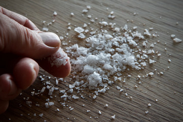 Sea salt on an oak table being picked up by the chef