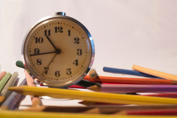 Set of colored pencils with alarm clock.