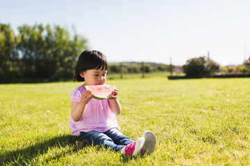 Fototapeta premium toddler girl eating watermelon at home garden