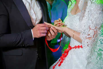 Groom puts wedding ring on bride's hand in church .Man puts a wedding ring on a bride's hand, close-up photo . Puts a ring on the bride's hand .