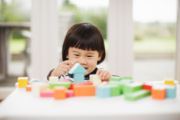 toddler girl playing toy blocks at home