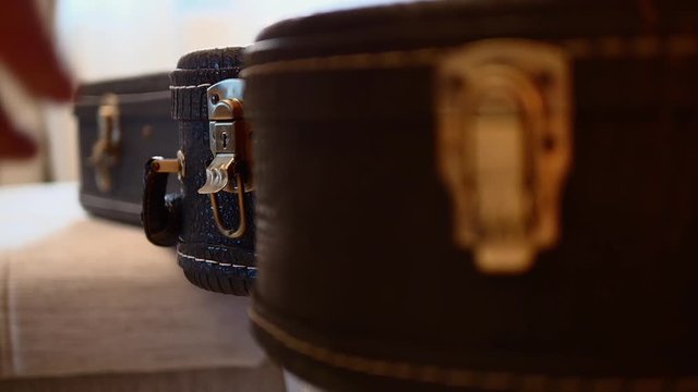 A hand with a golden ring on the finger is unlocking a black leather guitar case. Close up.