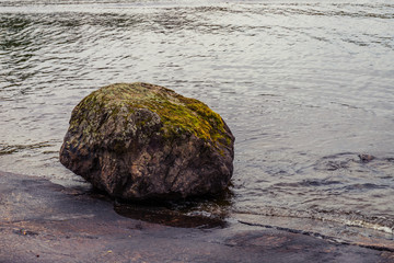 giant stone coverd with moss on the shore of the river