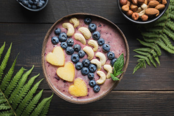 Fototapeta na wymiar Healthy breakfast banana and blueberry smoothie decorated with fruits in coconut bowl.
