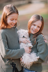 Little girls with a white puppy. A puppy in the hands of a girls