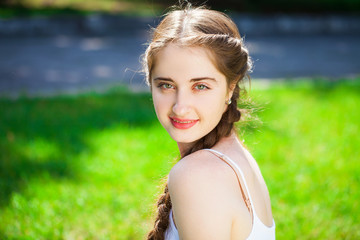 Portrait of a young beautiful brunette woman in on summer park background