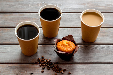 Coffee to go with muffin on wooden background