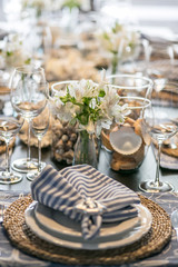 Table decoration with sea shells and napkin, plates and vase
