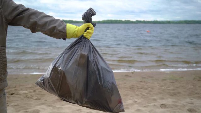 volunteer hands holding garbage bag on beach